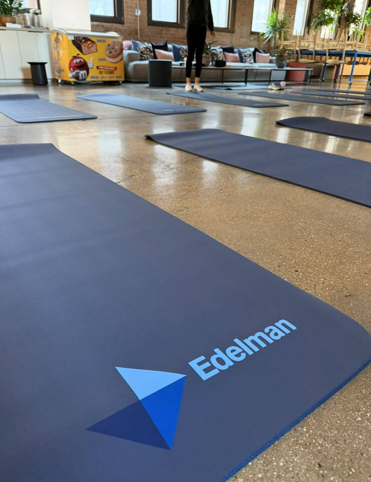 A group doing yoga in a bright, modern office space for an Edelman employee event