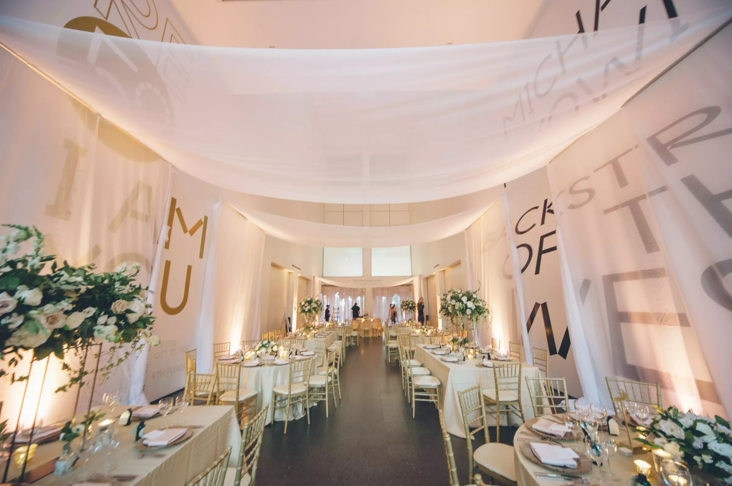 MCA Chicago event space arranged for a formal dinner with white draping, flowers, and gold chairs