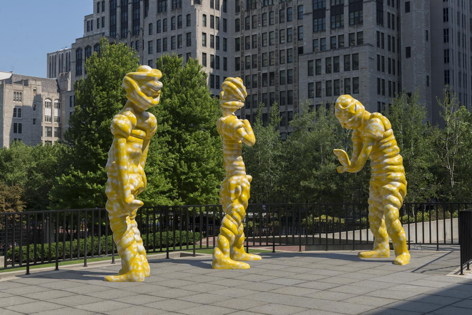 Yellow contemporary sculptures on the MCA Chicago terrace with trees and city buildings behind them