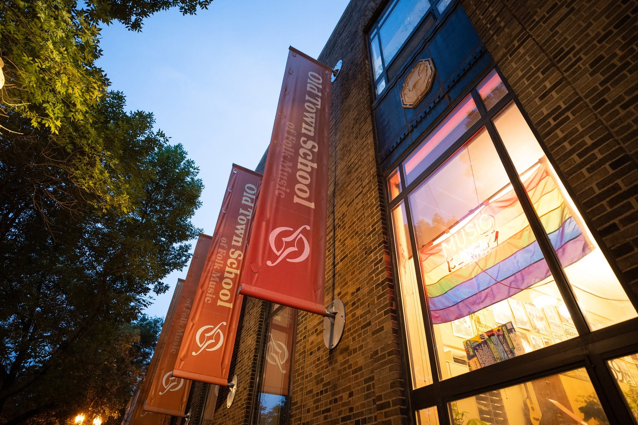 The Old Town School of Folk Music building at dusk, banners glowing in the windows.