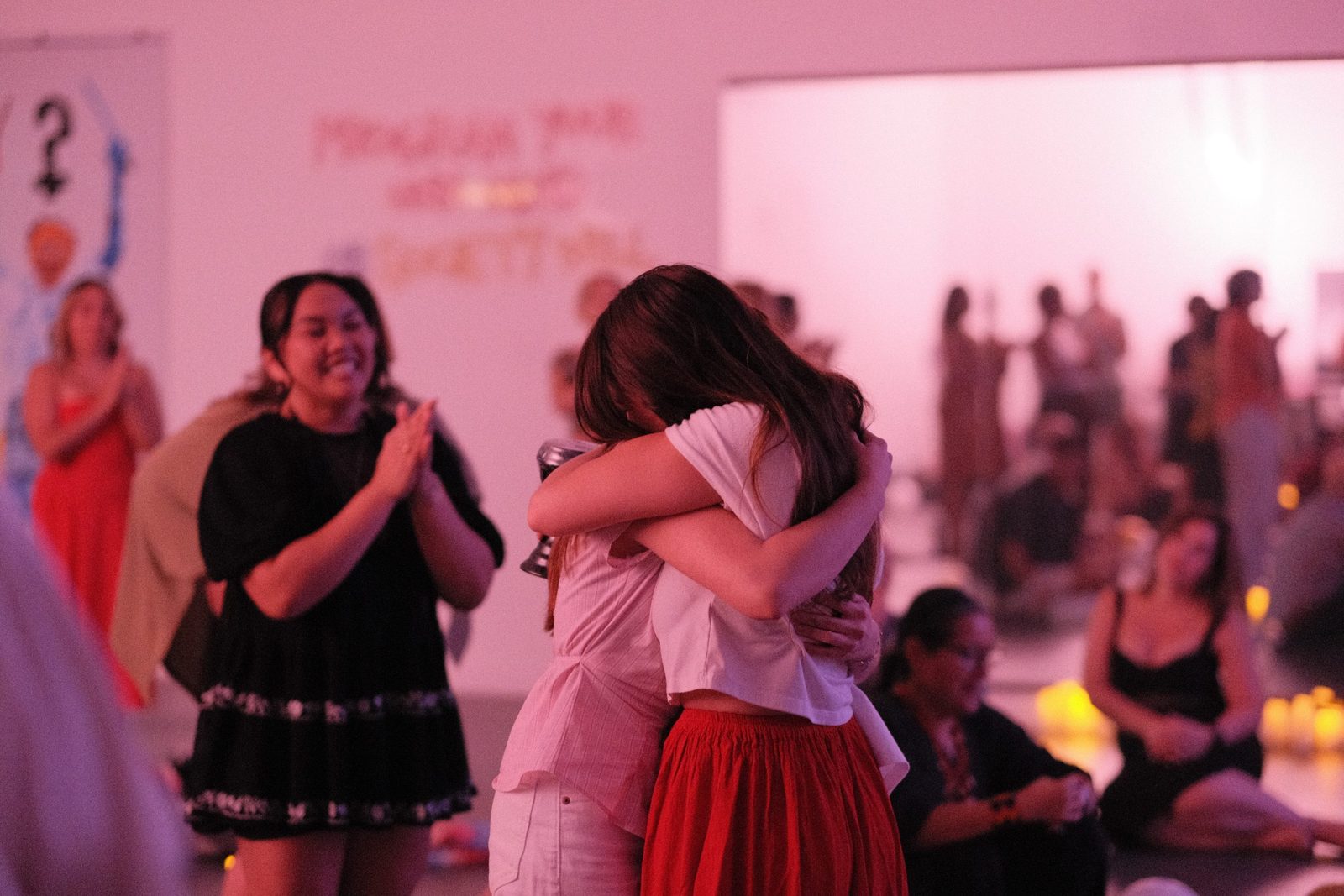 Two graduates embrace as the room applauds at the 2026 yoga teacher training graduation at LSP Studio in Pilsen